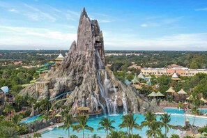 A large rock formation with a water slide and pool area. - Be Our Guest Multiple Pool Homes  (Kissimmee)