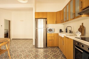 A compact kitchen with a stainless steel refrigerator, wooden cabinets, a microwave, and a sink. - Rustic Charm Hideaway • Balcony Oasis by SeaNRent (Tel Aviv-Yafo)