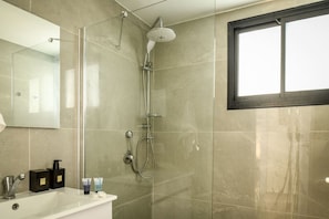 A bathroom with a glass shower enclosure, a white sink, and a large mirror.