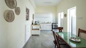 A modern kitchen with white cabinets, a dining table with chairs, and decorative woven wall hangings. - Your 2BR Green Oasis — Steps from Rabin Square (Tel Aviv)