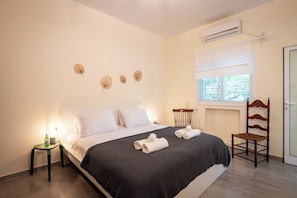 A bedroom with a bed, a nightstand, a chair, and a window with a view.