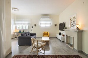 A living room with a sofa, a chair, a coffee table, a fireplace, and a TV.