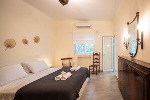 Una habitación de hotel con cama, sillón, escritorio y aire acondicionado.