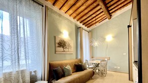A cozy living area with a sofa, bench, and dining table. - APARTMENT 'ORCHID' WHIT ONE BEDROOM.  (Firenze)
