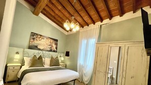 A bedroom with a bed, nightstands, a wardrobe, a chandelier, and a painting on the wall. - APARTMENT 'ORCHID' WHIT ONE BEDROOM.  (Firenze)
