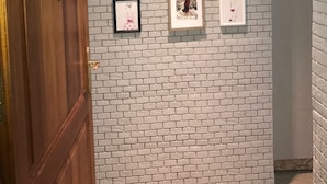 Un couloir avec un mur en briques et des œuvres d’art encadrées.