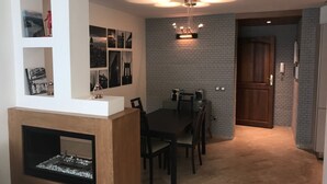 Un espace repas agrémenté d’un mur en briques, d’un lustre et d’une cheminée.