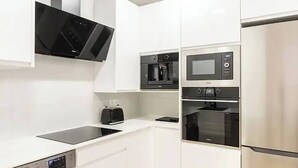 A modern kitchen with white cabinetry, a built-in microwave, a coffee maker, and a toaster.