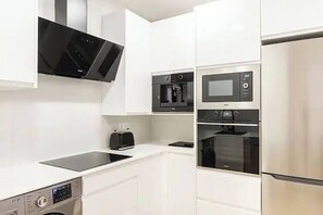 A modern kitchen with white cabinetry, a built-in microwave, a coffee maker, and a toaster.