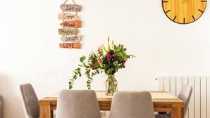 A dining table with four chairs, a wall clock, and a sign with motivational phrases.