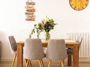 A dining table with four chairs, a wall clock, and a sign with motivational phrases.
