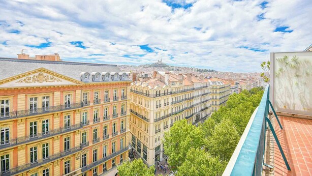 Un immeuble à plusieurs étages de style architectural classique, doté de balcons richement décorés et d’une cour intérieure.