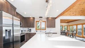 A modern kitchen with a large island, stainless steel appliances, and wooden cabinetry. - Great VIEWS! 10 mins to WISP, boat dock, hot tub, dog friendly, golf course. (Swanton)