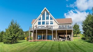 A two-story house with a balcony, large windows, and a covered patio area. - Great VIEWS! 10 mins to WISP, boat dock, hot tub, dog friendly, golf course. (Swanton)