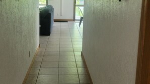 A hallway with tiled flooring and walls adorned with paddle-like wall decorations. - Newland's Cabin 5 (Baxter County)
