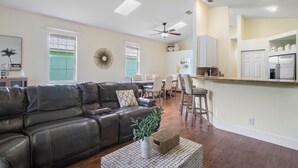 A spacious living room with a leather sofa, a dining area, and a kitchen with white cabinets and a refrigerator. - Jupiter's Beacon Villa. Less than 2 miles from the beach in the heart of Jupiter (Jupiter)