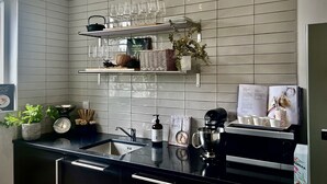 Uma cozinha moderna com bancada preta, eletrodomésticos de aço inoxidável e painel de azulejos.
