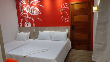 Habitación de hotel con una cama grande, dos almohadas, una puerta de madera y una pared roja con diseños blancos.