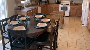 Una cocina moderna con armarios de madera, una mesa de comedor para cuatro personas y una isla central.