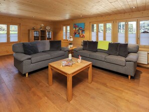 A wooden interior with two grey sofas, a wooden coffee table, and a painting on the wall.