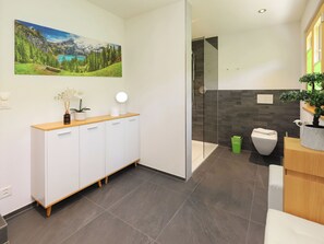 Un baño moderno con ducha, inodoro y un armario con espejo.