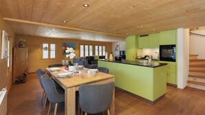 Una cucina moderna con mobili verdi, un tavolo da pranzo in legno con sedie e un'isola.