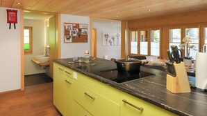 Una cucina moderna con un piano di lavoro nero, un fornello e una pentola sopra. Si nota un mobiletto in legno con cassetti e un lavello.