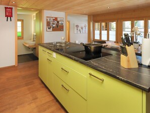 A modern kitchen with a black countertop, a stove, and a pot on it. There is a wooden cabinet with drawers and a sink.