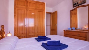 Une chambre à coucher avec une grande armoire en bois, une table de chevet avec une lampe et un miroir au-dessus d’une commode.