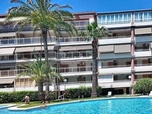 Ein mehrstöckiges Hotel mit Balkonen, einem Pool und Palmen.