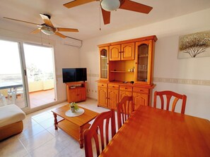 A living room with a wooden dining table, chairs, a TV, and a ceiling fan. - Dianium by Interhome (Dénia)