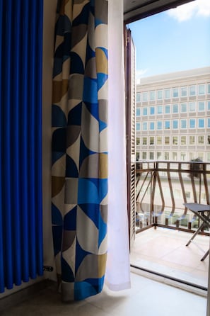 Una stanza con vista su un edificio, attraverso una finestra con tenda.