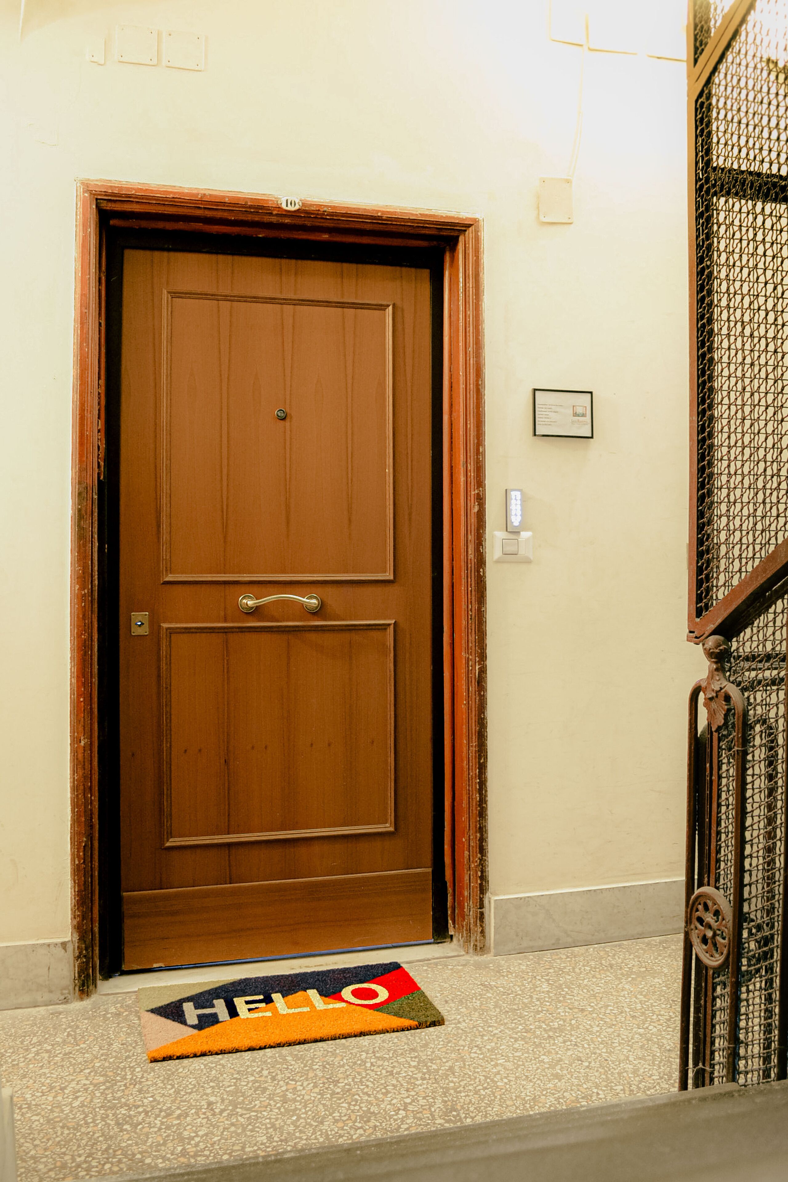 A wooden double door with a doormat that reads "HELLO".