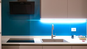 A modern kitchen with a built-in oven, a sink with a faucet, and a countertop with a basket of snacks. - Lele Rooms Termini (Rome)