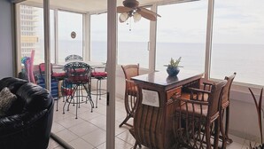 Ein Balkon mit Tisch und Stühlen, einem Deckenventilator und Blick auf das Meer.