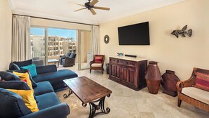 A spacious living room with a sofa, a coffee table, and a TV mounted on the wall.