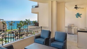 A balcony with wicker furniture, a ceiling fan, and a kitchen area with a grill.