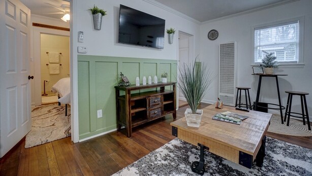 Una sala de estar con un televisor montado en la pared, una mesa de centro de madera y una pared de acento verde.