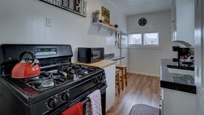 Una cocina con estufa a gas, microondas y un reloj en la pared.