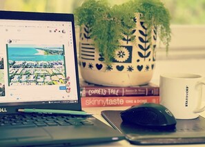 A laptop displaying a map, a mouse, a coffee mug, a potted plant, and books on a desk.
