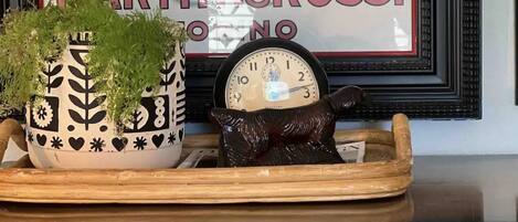 A decorative tray with a clock and a plant on a wooden surface.