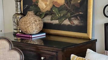 A bedroom with a bed, a nightstand with a lamp, a woven basket, and a framed painting.