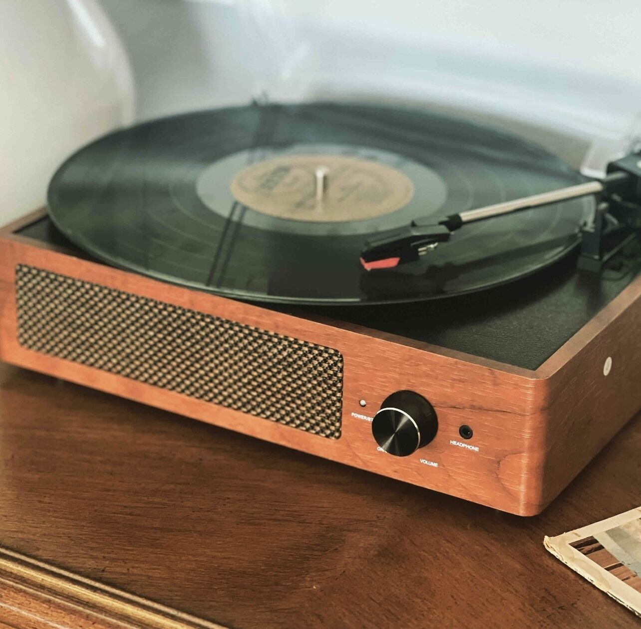 Une platine vinyle ancienne, dotée d’un socle en bois et d’une grille de haut-parleur.