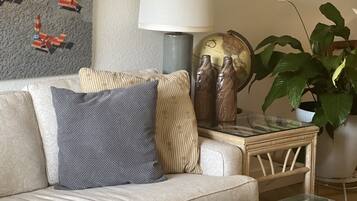 Un salon avec un canapé, des coussins, une lampe, un globe terrestre et une plante.