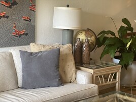 Una sala de estar con sofá, cojines, una lámpara, un globo terráqueo y una planta.