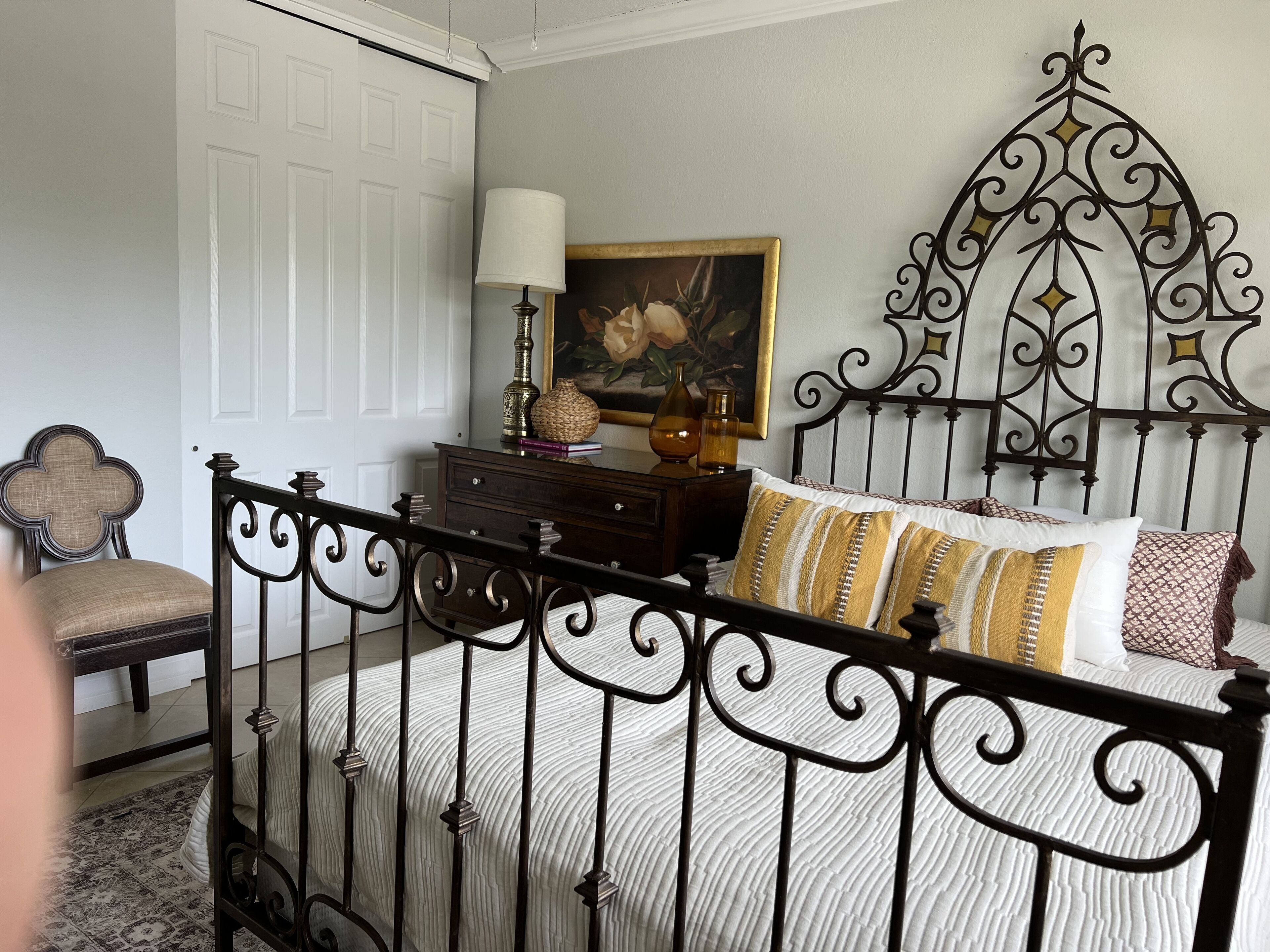 Une chambre à coucher avec un lit, une chaise, une commode et un tableau accroché au mur.