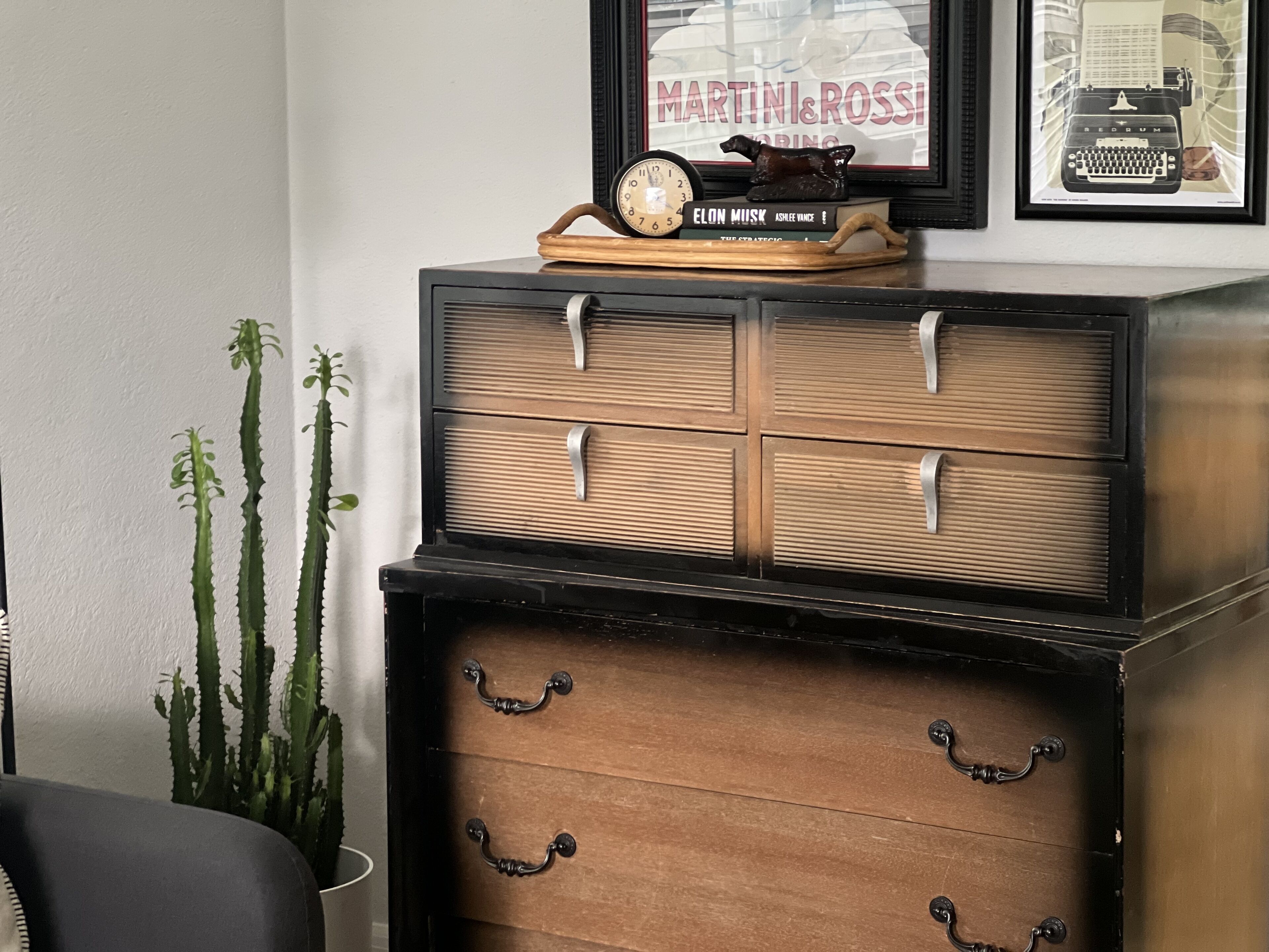 A vintage-style dresser with four drawers and a clock on top.