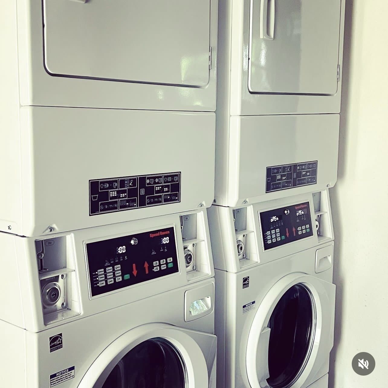 A stack of white washing machines with control panels and a notice label.
