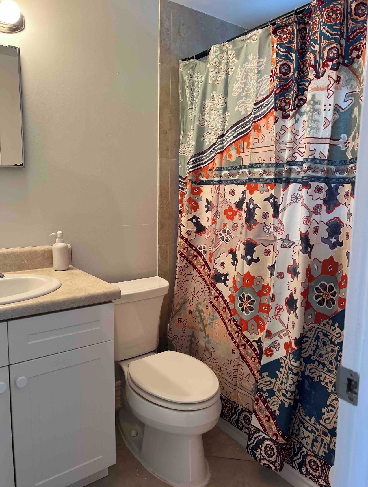 A bathroom with a toilet, sink, and a shower curtain with a patterned design.