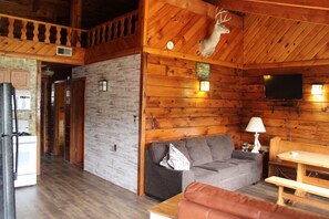 A log cabin interior with a wooden ceiling, a gray sofa, a wooden table, and a mounted deer head. - Dun Rovin Duplex1 On the Chippewa Flowage  (Hayward)